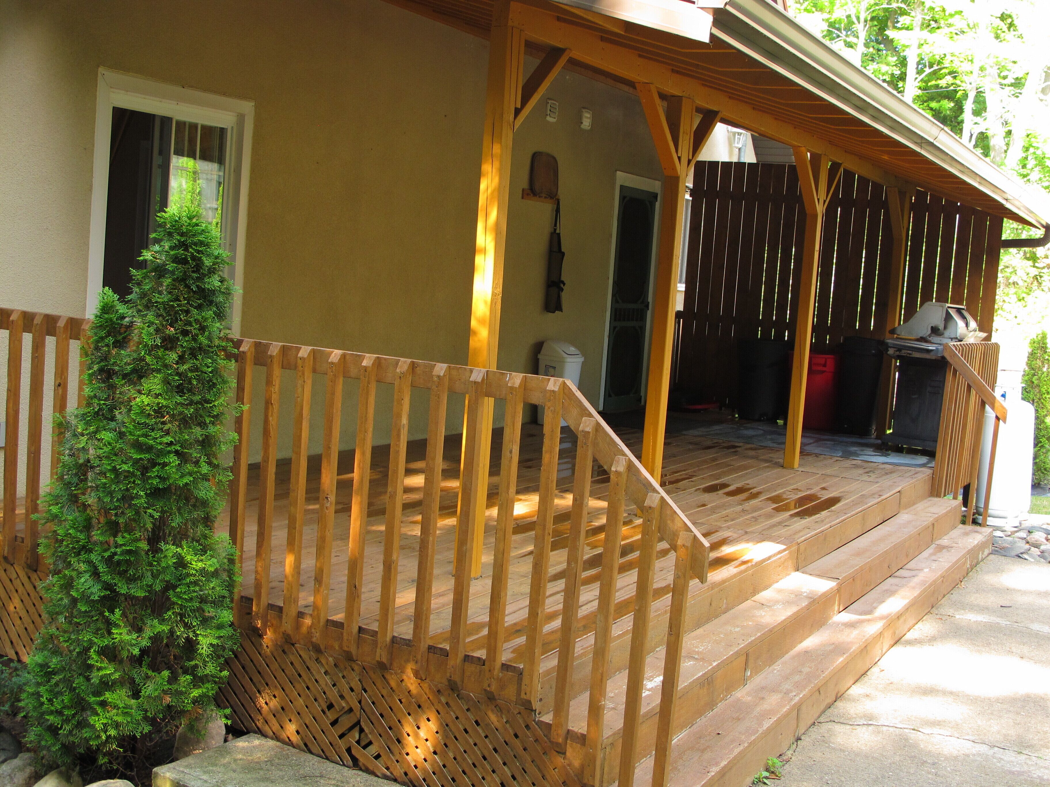A wooden deck with a staircase leading to a covered porch area.