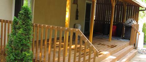 A wooden deck with a staircase leading to a covered porch area.