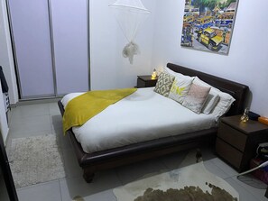 A bedroom with a bed, nightstands, a lamp, a wall hanging, and a rug.