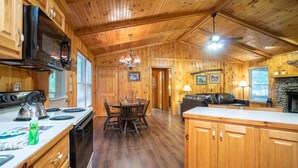 A wooden cabin interior with a kitchen, dining area, and living room.