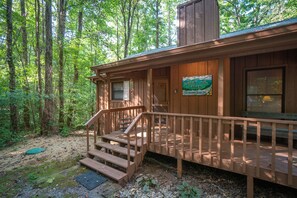 A wooden cabin with a porch, steps, and a sign indicating it's on the creek.