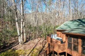 A wooden cabin with a balcony, surrounded by a forest.
