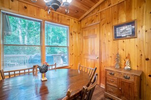 A wooden-paneled room with a dining table, chairs, and a cabinet.