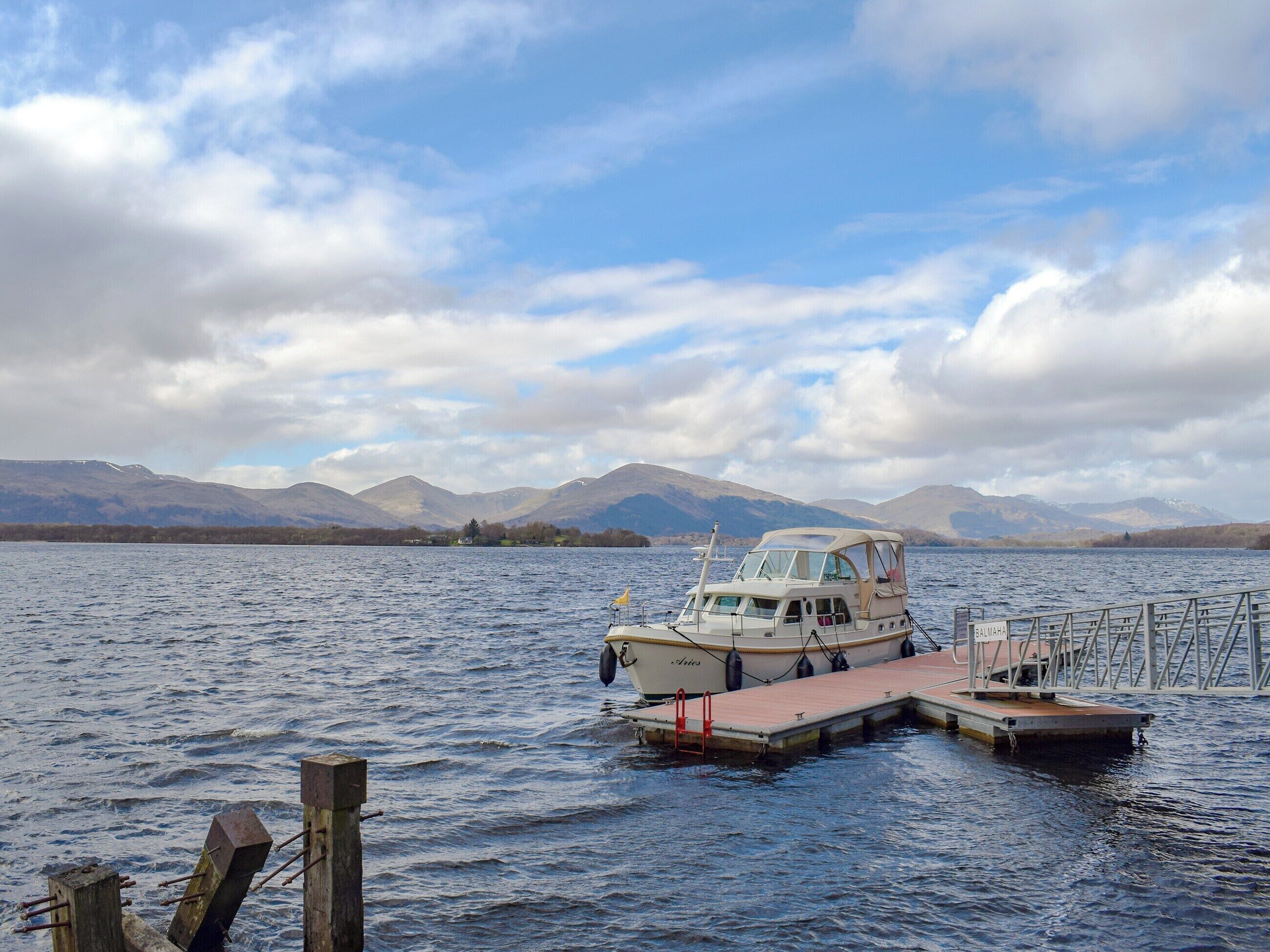 Un bateau était amarré à un quai, avec des montagnes en arrière-plan.