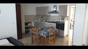 Eine kompakte Küche mit Esstisch und Stühlen, ausgestattet mit einem Herd, Backofen und einer Mikrowelle.