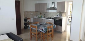 Une cuisine compacte comprenant une table et des chaises, une cuisinière, un four et un four à micro-ondes.