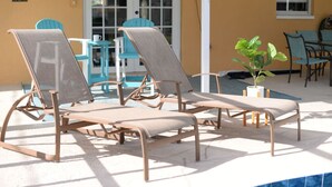 Ein Poolbereich mit Liegestühlen und einer Pflanze im Topf.