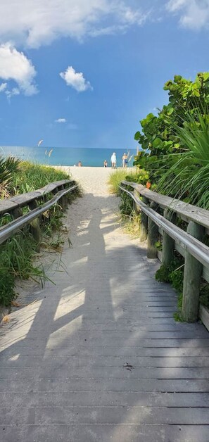 A wooden boardwalk leading to a beach with a clear sky and calm sea. - Heated Pool | Pet Friendly | Beach Gear | Big Yard (Englewood)