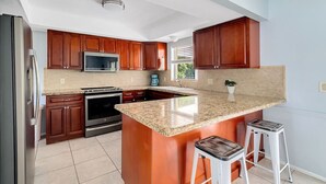 Eine Küche mit Holzausstattung, einer Granit-Arbeitsplatte, einem eingebauten Backofen, einer Mikrowelle und einer Kaffeemaschine.
