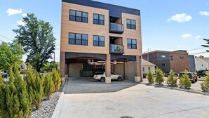 A multi-story building with a modern design, featuring a covered parking area and a white vehicle parked inside. - 1BR I King + Sofa I Walk Shops + DT TC (Traverse City)