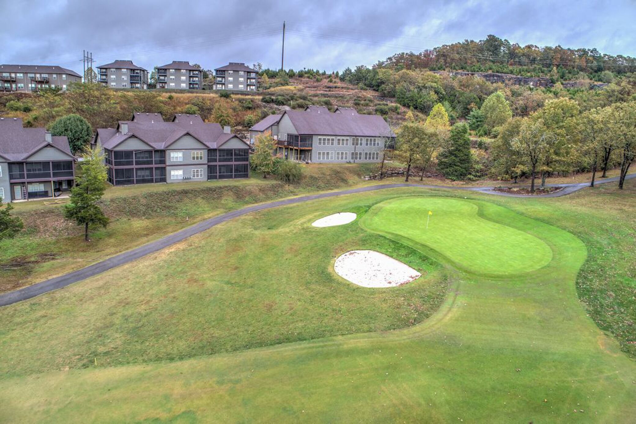 Un campo da golf con bunker e una strada che conduce al club house.