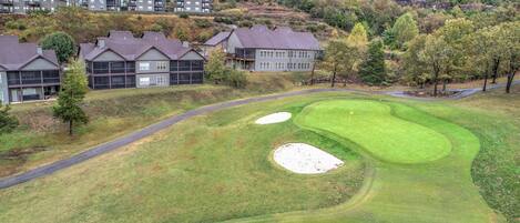 Un campo da golf con bunker e una strada che conduce al club house.