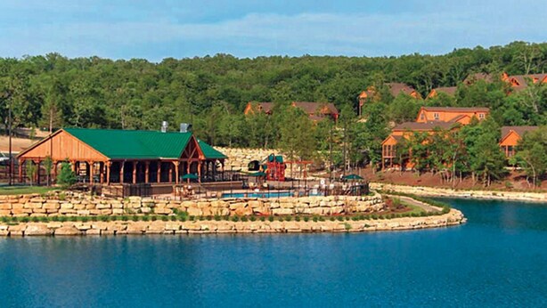 A lakeside resort with a wooden pavilion, a pool, and several houses in the background. - Gorgeous Golf Views, Quiet/Large, Resort and Pools (Reeds Spring)