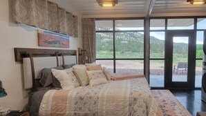 A bedroom with a large bed, an open sliding door to a balcony, and a washing machine.
