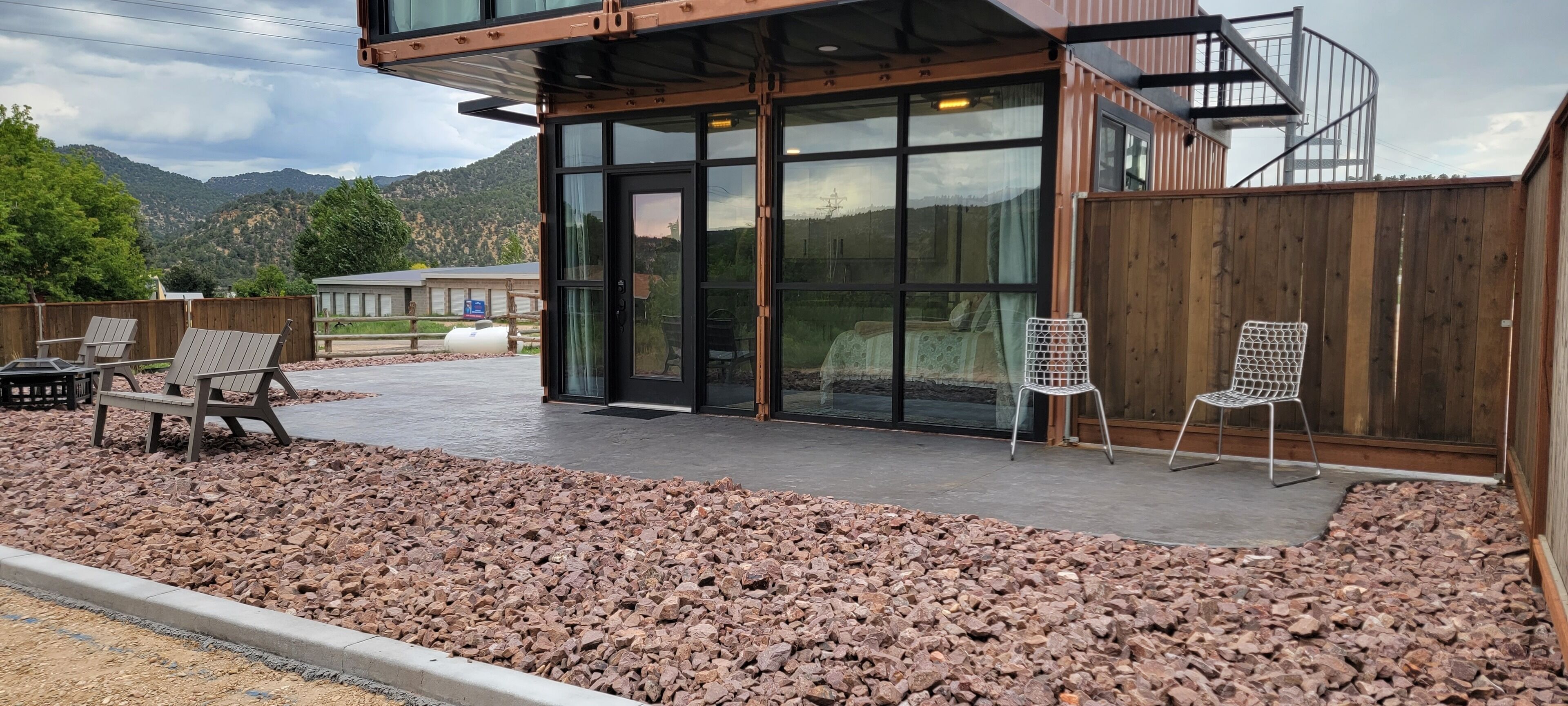 A modern building with a covered patio, outdoor seating, and a view of mountains.