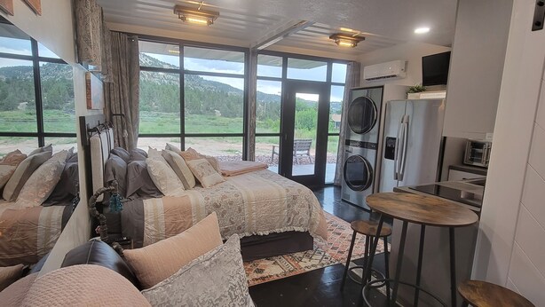 A bedroom with a large bed, a small table, and a washing machine.