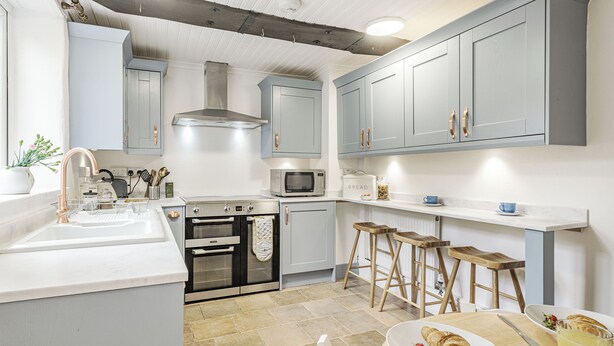 A modern kitchen with grey cabinets, stainless steel appliances, and a breakfast setup on the counter. - 4 bedroom accommodation in Bacton, Norwich (Bacton, Norwich)