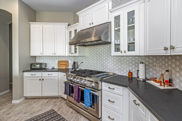Enjoy cooking in this kitchen with sleek cabinetry, a range hood, and a kitchen island with oven and microwave.
