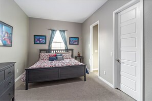 Cozy retreat with a dark bed frame, patterned bedspread, and framed artworks adorning the walls.