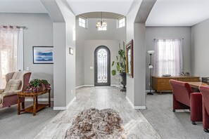Experience comfort and style in this beautifully appointed space with a high ceiling, plush armchair, and decorative table.