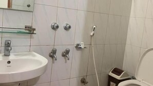 Un baño pequeño con lavamanos blanco, inodoro y zona de ducha.