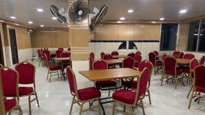 Un comedor amplio con varias mesas y sillas tapizadas en rojo.