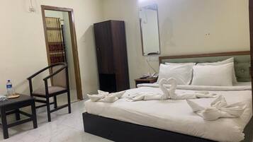 Una habitación de hotel con cama, una silla, armario y espejo.