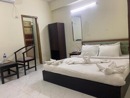 Una habitación de hotel con cama, una silla, armario y espejo.
