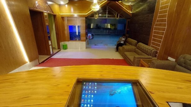 Un vestíbulo de hotel con mostrador de recepción, una zona de estar y vistas a la cocina.