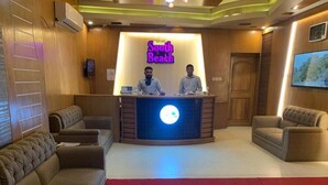 Una zona de recepción con un mostrador, dos empleados y un gran cartel iluminado que dice "Hotel South Beach".