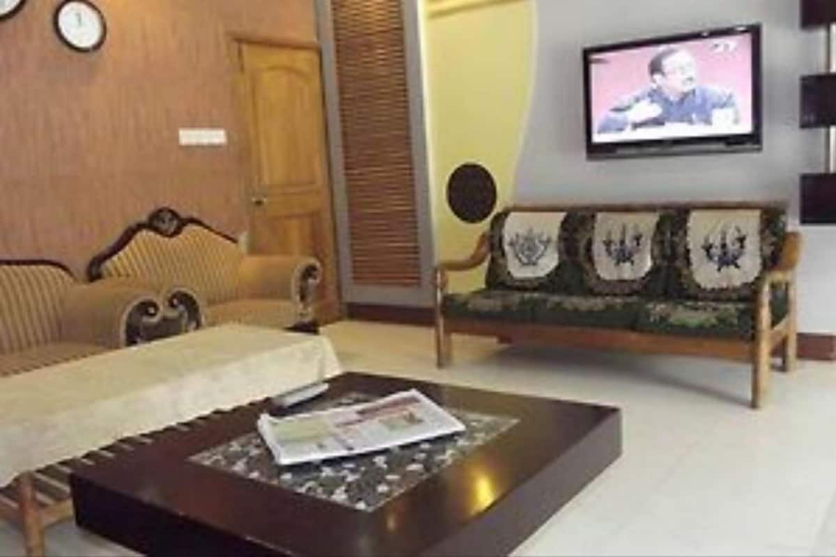 Un salon comprenant un canapé, une table basse avec un magazine, un téléviseur fixé au mur et une porte.
