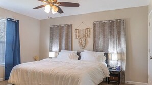 A bedroom with a bed, two bedside tables, a ceiling fan, and curtains. - Quarry Downtown Airport 10 mins or less (San Antonio)