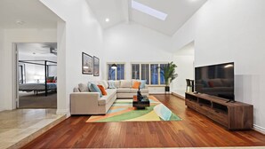 Un salon spacieux avec un canapé, un téléviseur et un plancher en bois.