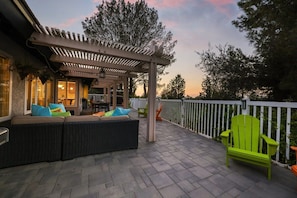 An outdoor patio with a covered seating area, a dining table, and a bright green chair. - Family Retreat w/ Hot Tub, Big Back Deck & Games! (Poway)