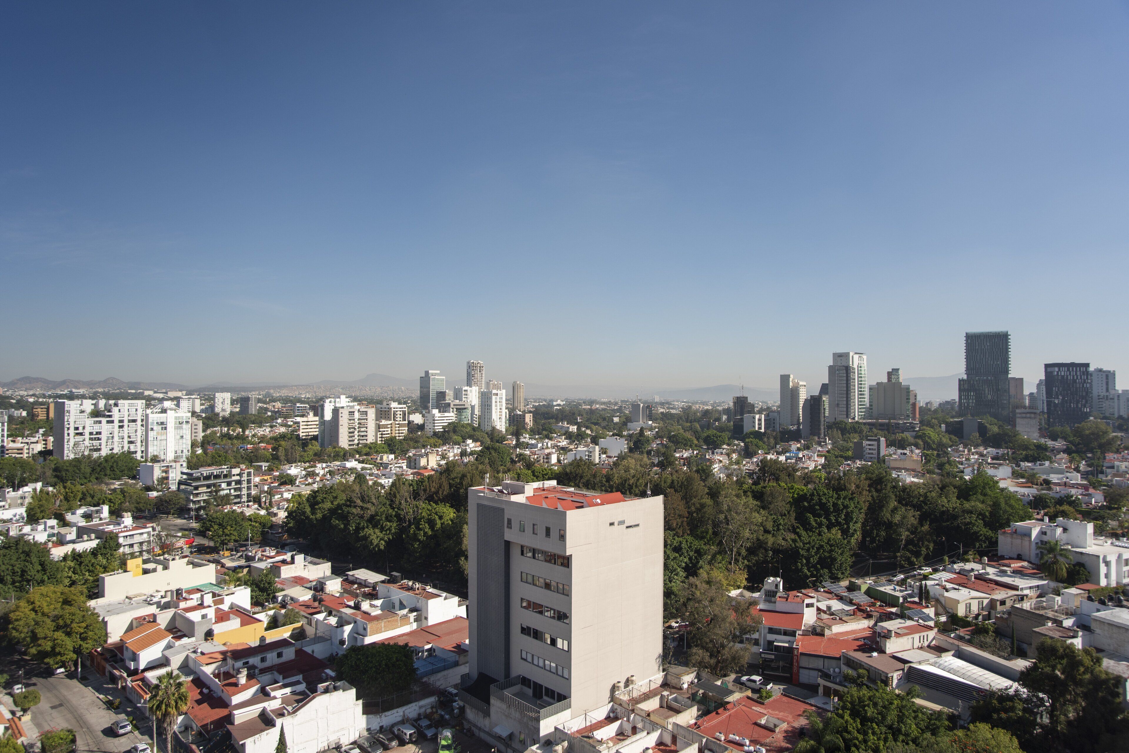 A cityscape with a prominent white building in the foreground, surrounded by residential buildings and greenery.