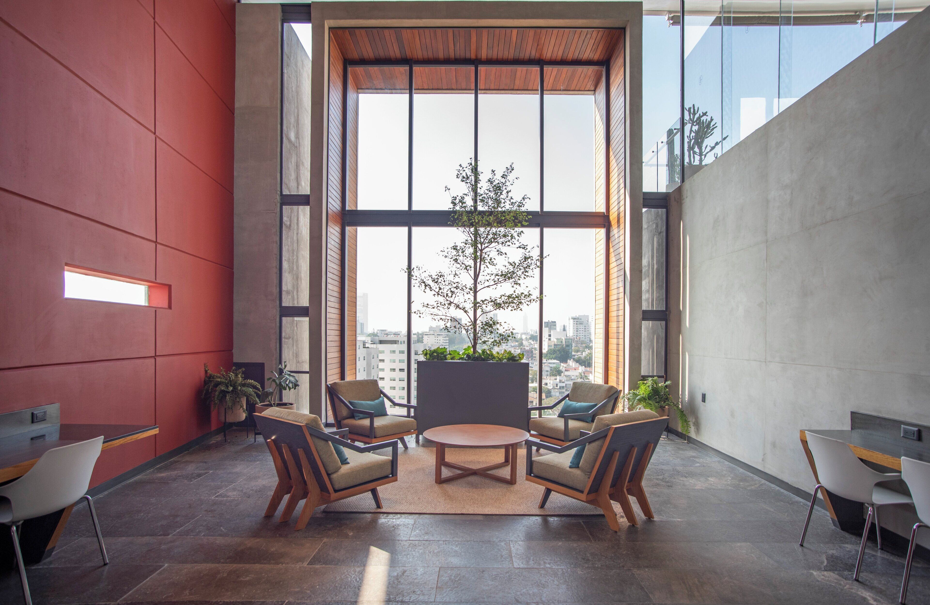 Un intérieur moderne avec de grandes fenêtres, un espace salon central et une vue sur le paysage urbain.