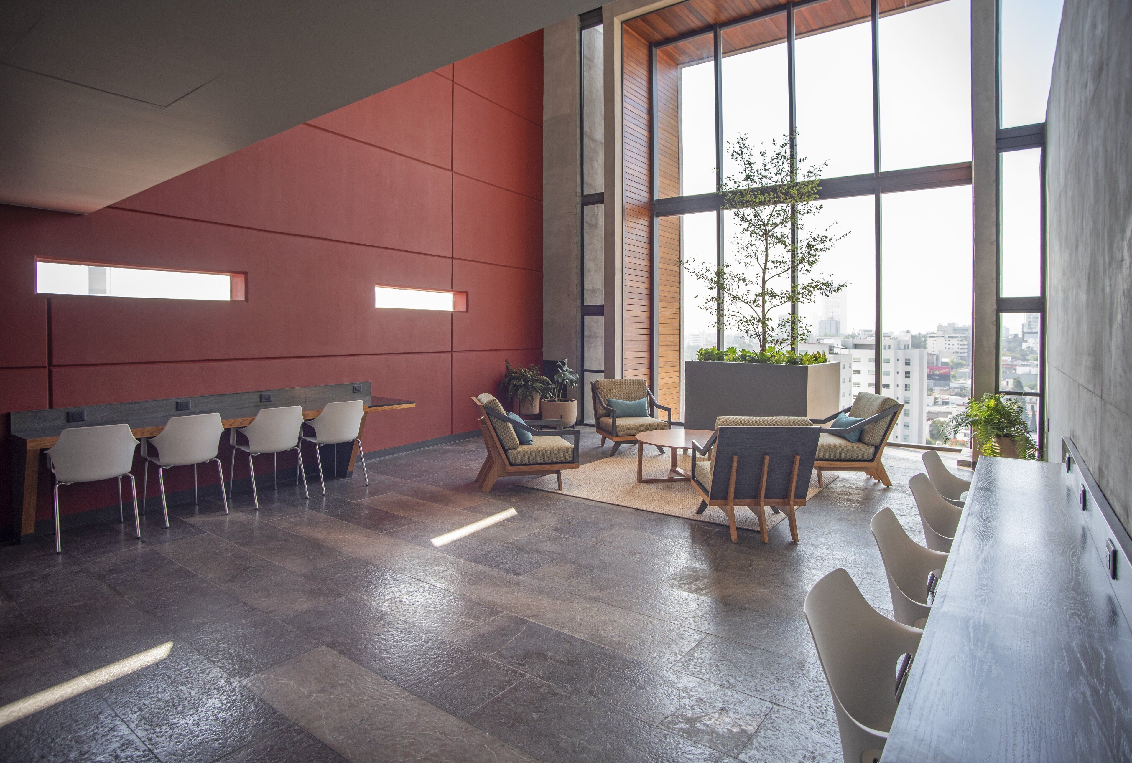 A modern office space with a long table, several chairs, and a large window with a view of the city.