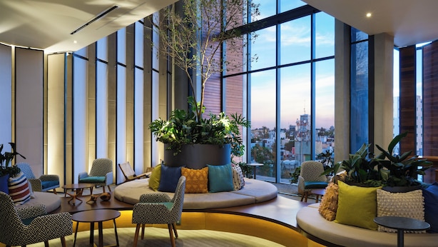 A modern lounge area with seating arrangements, large windows, and indoor plants. - voco Guadalajara Neruda by IHG (Guadalajara)