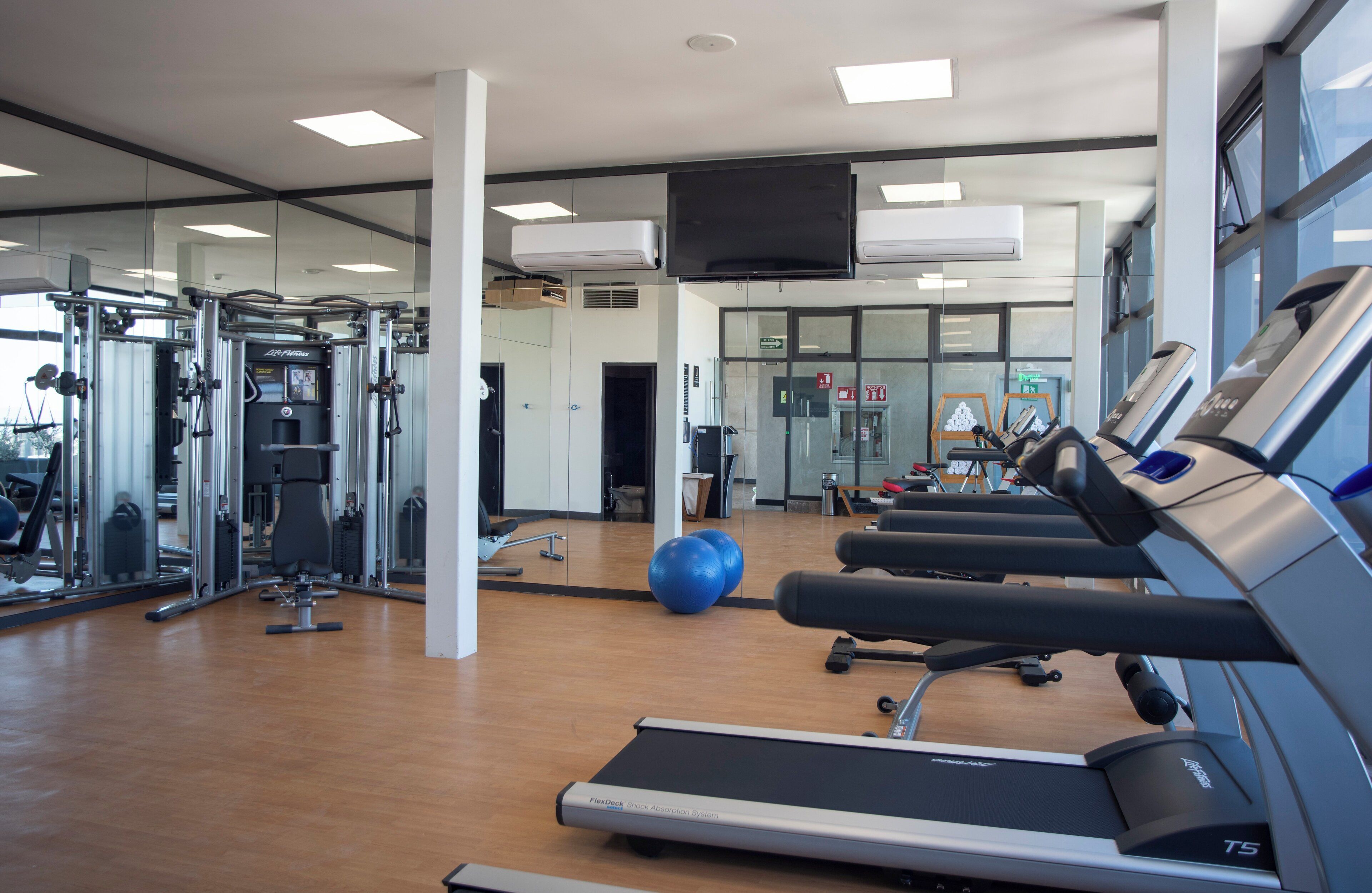 A gym with treadmills, weight machines, and exercise balls.