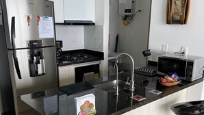 A modern kitchen with a central island, stainless steel appliances, and a microwave. - Beautiful condo with views of the beach (Cartagena)
