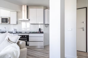 Una cucina moderna con mobili bianchi, un forno a microonde integrato e una macchina per il caffè.
