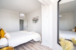 Una camera da letto moderna con due letti, un grande specchio e una mensola sospesa per piante.