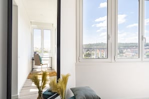 Una stanza luminosa con ampie finestre, vista su un ponte e una sedia con cuscino.