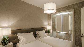 Une chambre à coucher avec un grand lit, une table de chevet, une lampe et une porte.