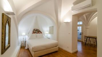 Un dormitorio con una cama grande, una mesita de noche, una lámpara, un espejo y un techo abovedado.