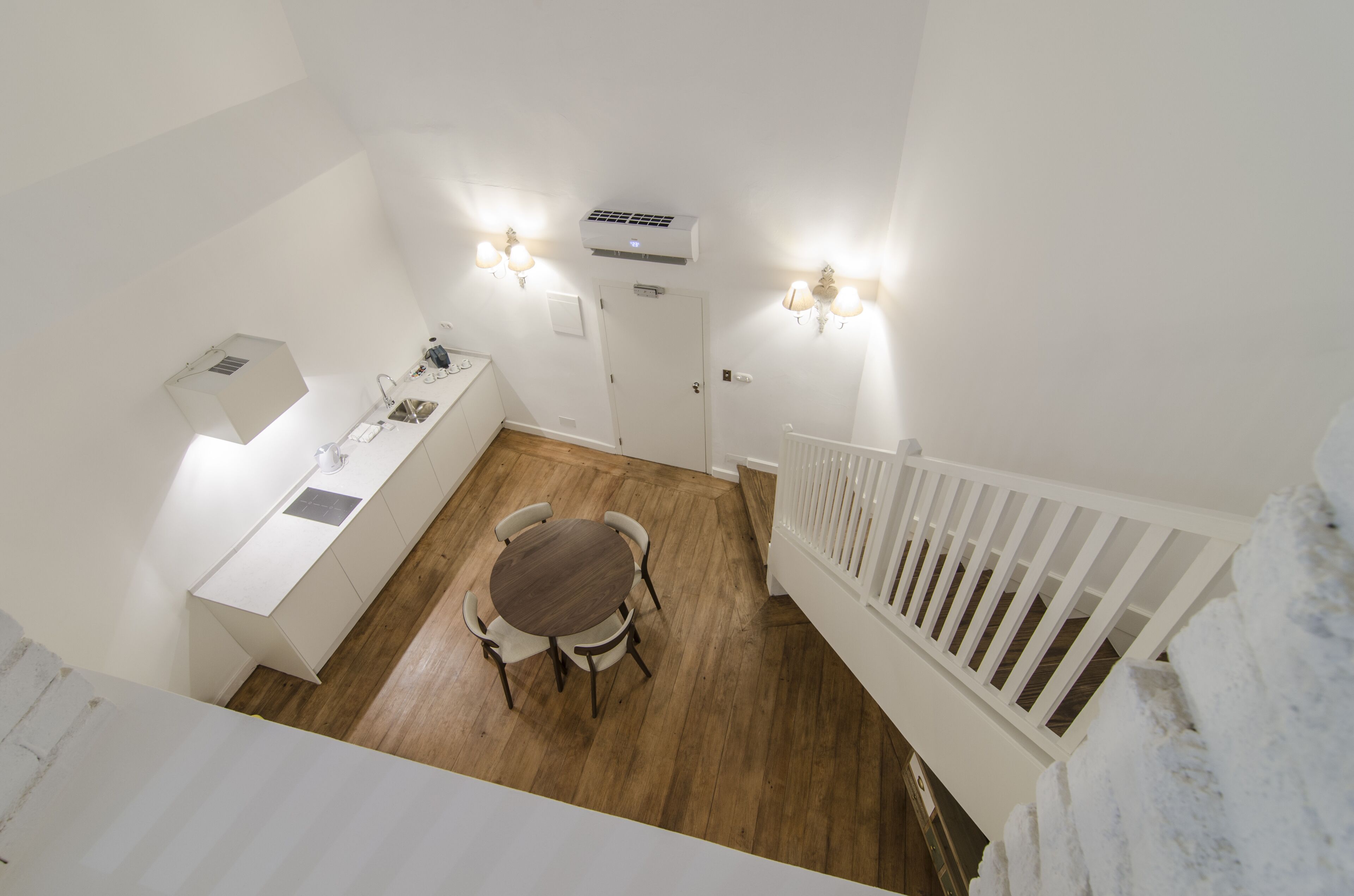A compact kitchen with a dining table, white cabinetry, and a white railing.
