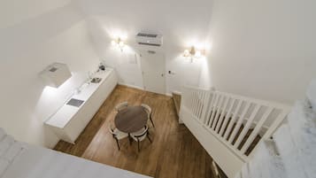 A compact kitchen with a dining table, white cabinetry, and a white railing.