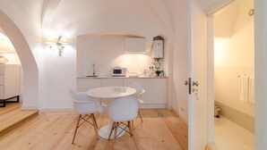A modern kitchen with white cabinetry, a round dining table, and two white chairs. - Casa Morgado Esporão (Évora)