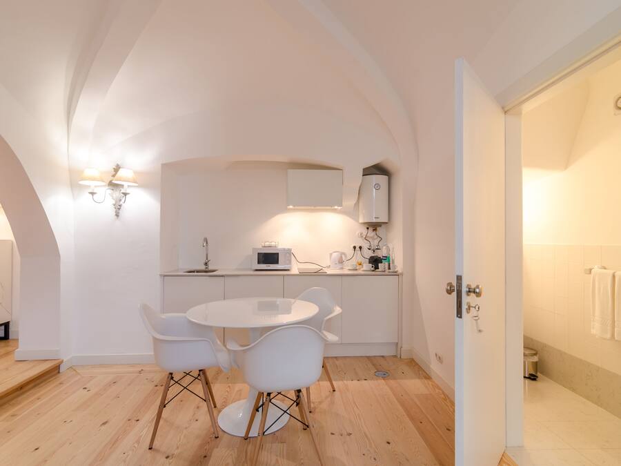 A modern kitchen with white cabinetry, a round dining table, and two white chairs.