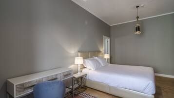 A bedroom with a bed, a desk, a chair, and two bedside lamps.